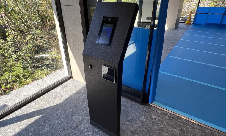 マンション入口のオートロック操作板。 黒い大理石調の自立型のパネルで、操作パネル面が少し斜めに傾いている。