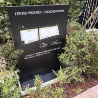 マンションの外にあるスタンドサイン。 およそ1メートルほどの高さの縦に長いパネル。 黒いパネル面には、マンションの全体図とともに、一団地の範囲や公開空地範囲などが表示されている。
