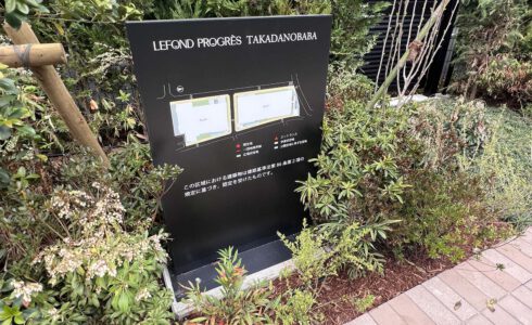マンションの外にあるスタンドサイン。 およそ1メートルほどの高さの縦に長いパネル。 黒いパネル面には、マンションの全体図とともに、一団地の範囲や公開空地範囲などが表示されている。