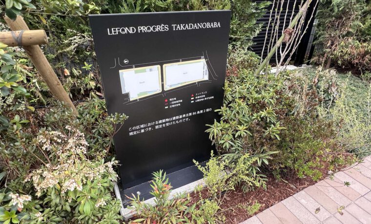 マンションの外にあるスタンドサイン。 およそ1メートルほどの高さの縦に長いパネル。 黒いパネル面には、マンションの全体図とともに、一団地の範囲や公開空地範囲などが表示されている。