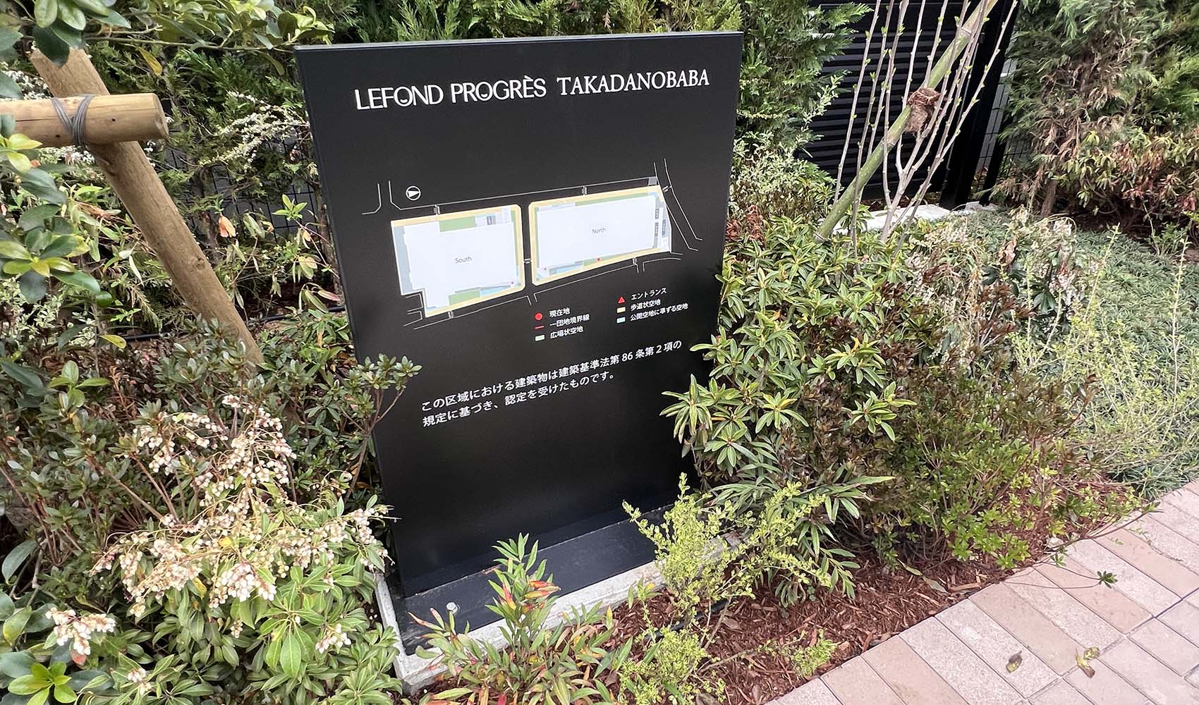 マンションの外にあるスタンドサイン。 およそ1メートルほどの高さの縦に長いパネル。 黒いパネル面には、マンションの全体図とともに、一団地の範囲や公開空地範囲などが表示されている。