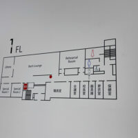 白い壁についている、カッティングシールのフロア案内表示。 1階の簡フロアマップが表示されている。