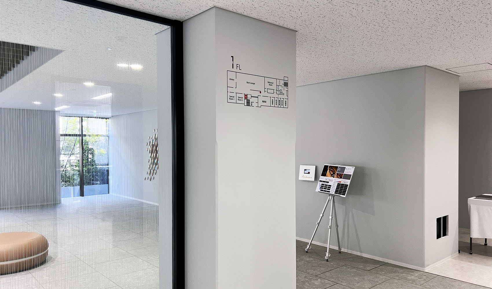白い壁についている、カッティングシールのフロア案内表示。 1階の簡フロアマップが表示されている。
