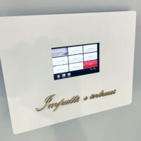 壁面アート照明操作板。 壁についた白いボックスの中央に、操作用のタッチパネルがある。その下には「Impatti e intrecci」と書かれたゴールド色のアクリル切文字が付いている。